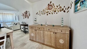 Un salon avec un meuble en bois, un canapé et des œuvres d’art décoratives accrochées au mur.