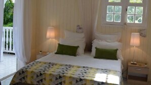 A bedroom with a bed, two bedside tables, a hanging lamp, and a window with curtains.