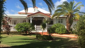 A two-story house with a white facade, red roof, and a covered porch.