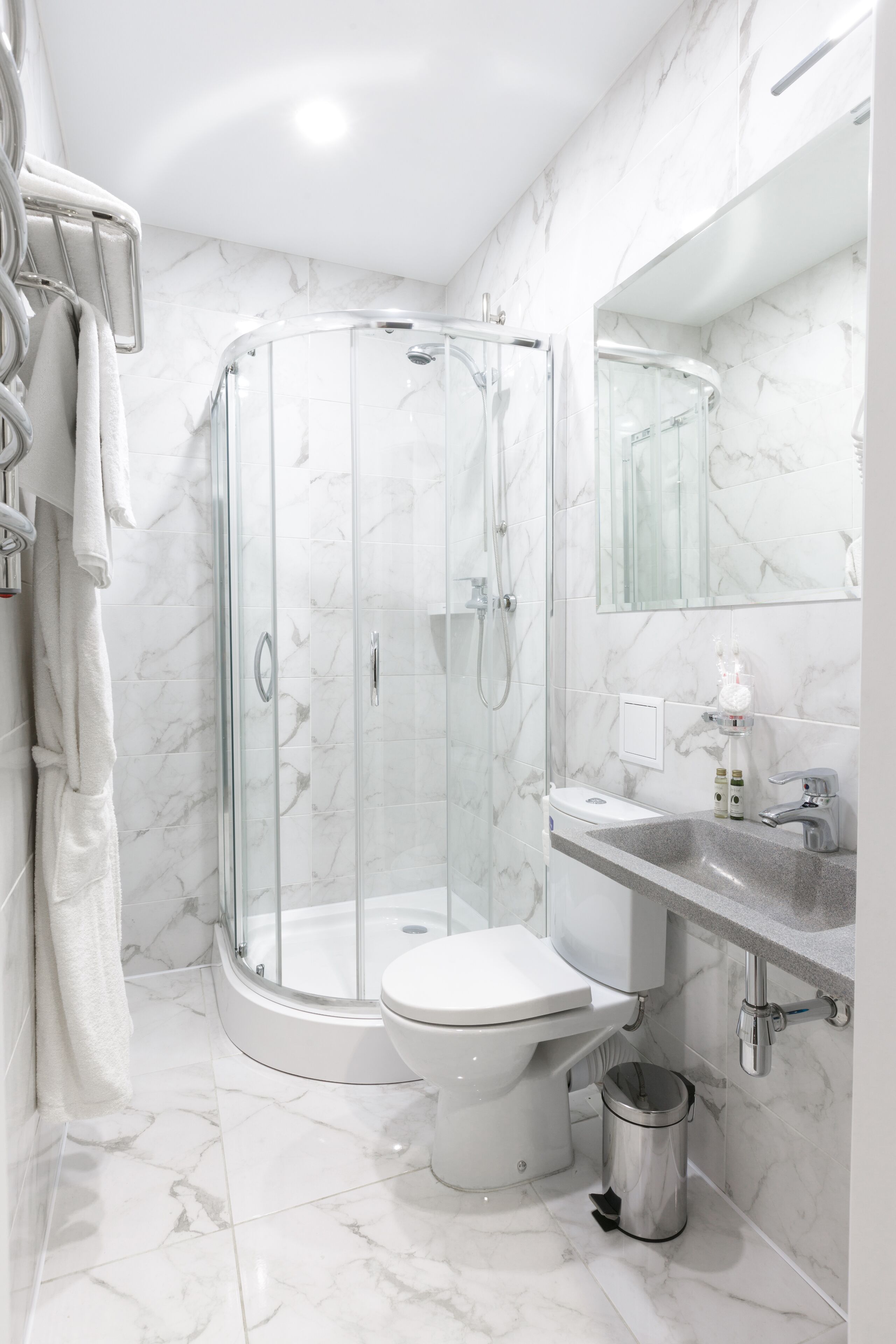A modern bathroom with a glass-enclosed shower, a toilet, a sink, and a mirror.