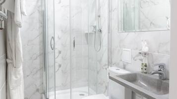 A modern bathroom with a glass-enclosed shower, a toilet, a sink, and a mirror.