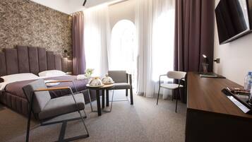 Ein modernes Hotelzimmer mit einem großen Bett, einem Schreibtisch, einem Stuhl und einem Fernseher.