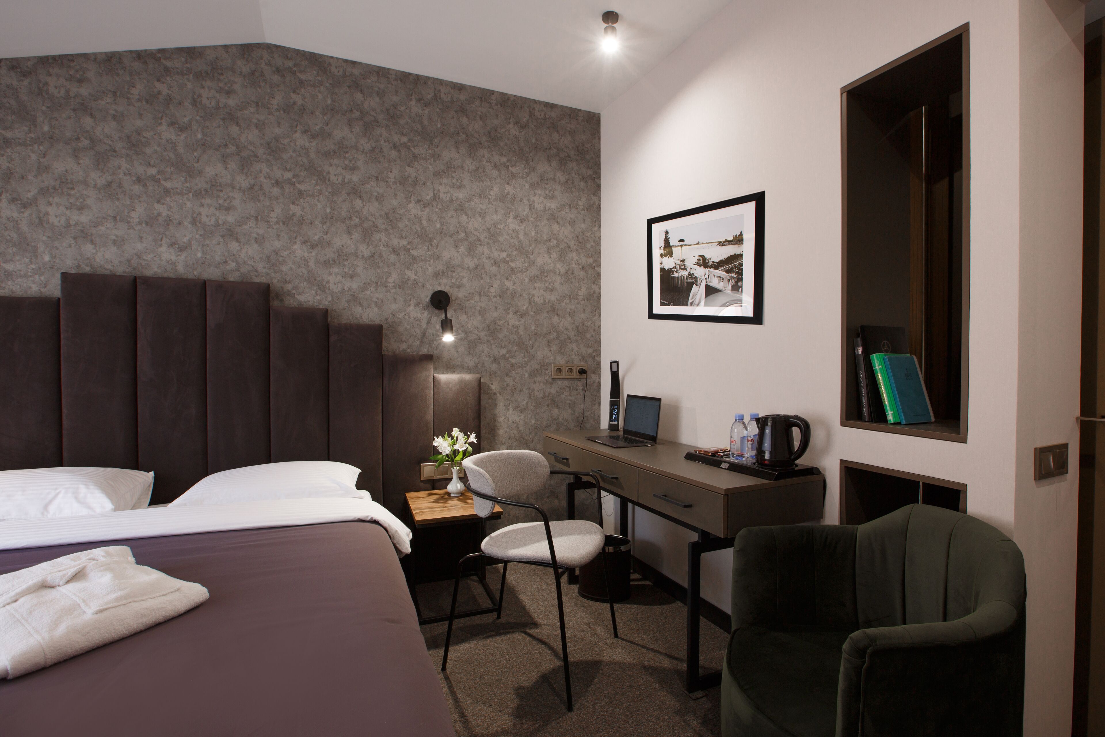Habitación de hotel con cama, escritorio, silla, ordenador portátil, un cuadro en la pared y ventana.