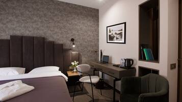 Habitación de hotel con cama, escritorio, silla, ordenador portátil, un cuadro en la pared y ventana.