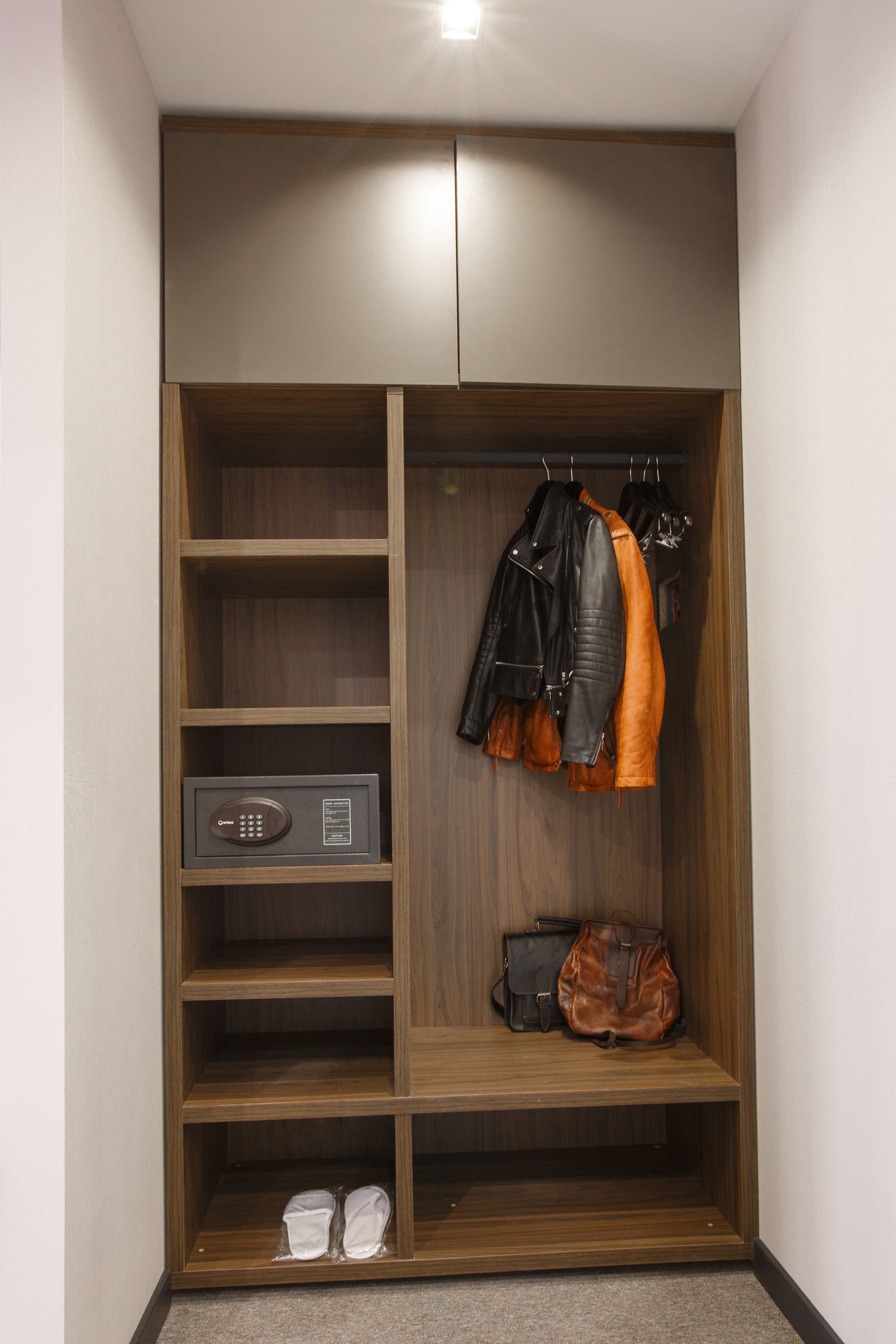 A walk-in closet with wooden shelves, a safe, and hanging garments.
