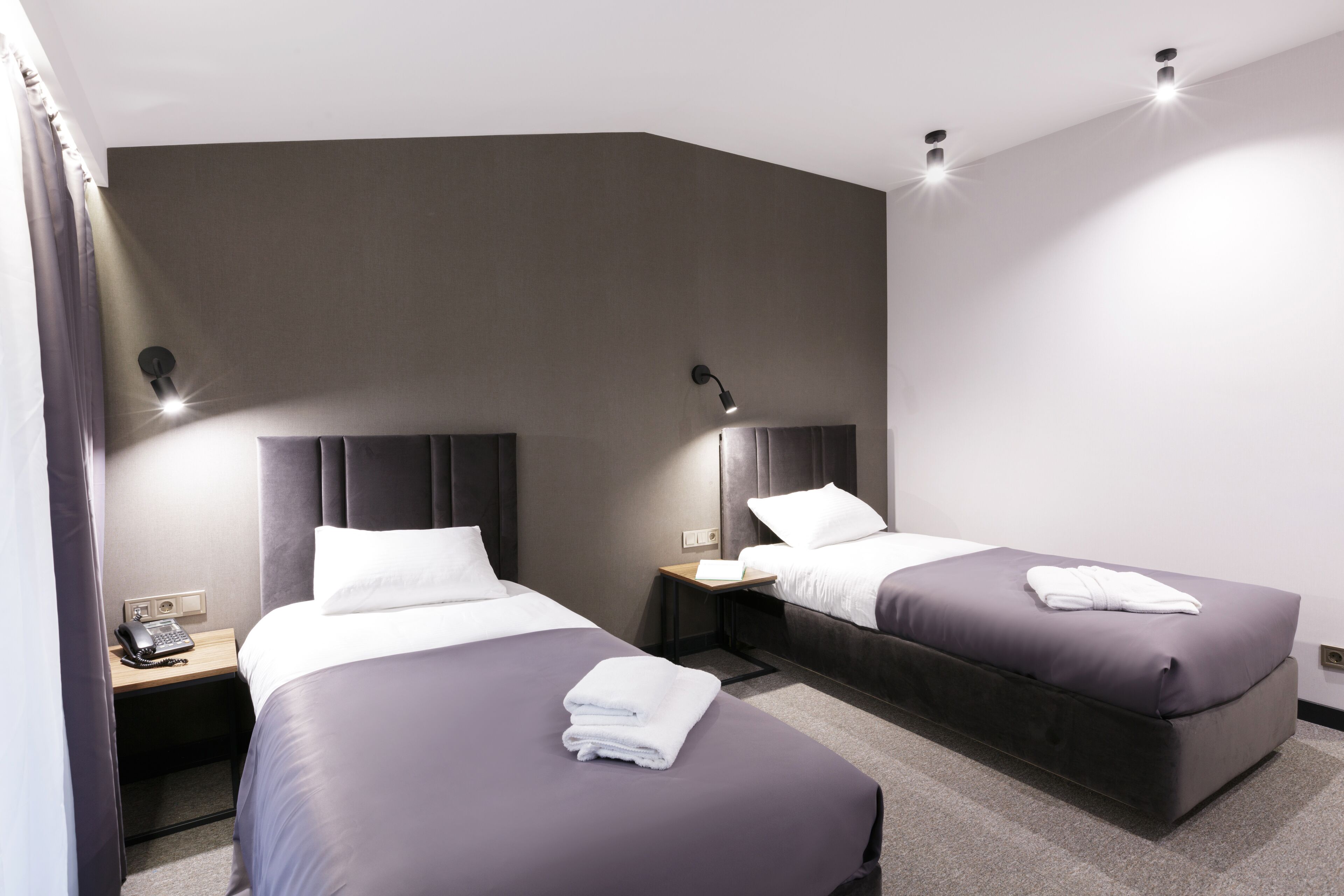A modern hotel room with two beds, a desk, and a telephone.