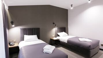 A modern hotel room with two beds, a desk, and a telephone.