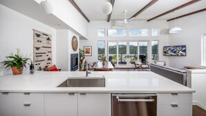 Una cocina moderna con una isla grande, un comedor con vistas y un espacio de sala con televisor.