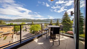 A balcony with a view of a lake and mountains, featuring a table and chairs. - Hawks Perch - New Downtown Modern, Panoramic View (Hood River)