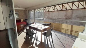 Ein Essbereich mit Tisch und Stühlen, eine rote Couch und Blick durch ein vergittertes Fenster.