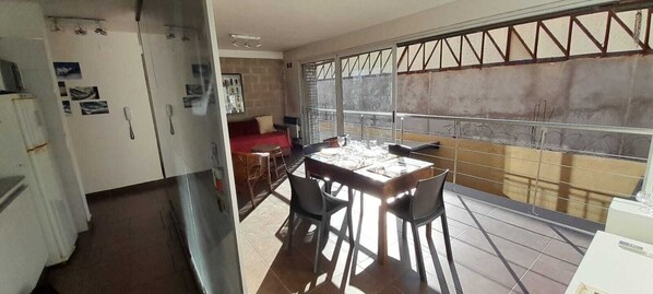 Un comedor con una mesa y sillas, un sofá rojo y vistas a través de una ventana con barrotes.