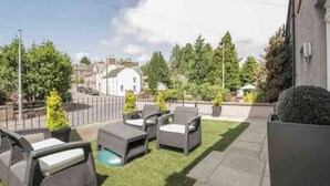 Une terrasse extérieure avec des meubles en osier gris et une petite piscine.