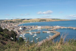 A coastal town with a marina, buildings, and a hilly landscape in the background. - Modern comfort in traditional Scottish village (Auchenblae)