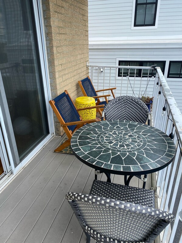 A balcony with a round table, two chairs, and a yellow stool.