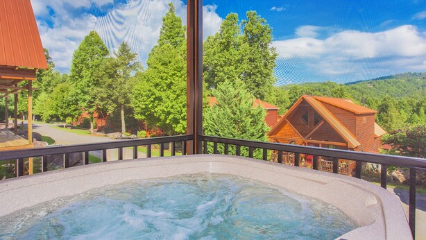 Un bain à remous avec vue sur une forêt et des maisons.