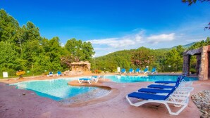 Un espace piscine doté de plusieurs chaises longues et d’une petite cascade décorative.