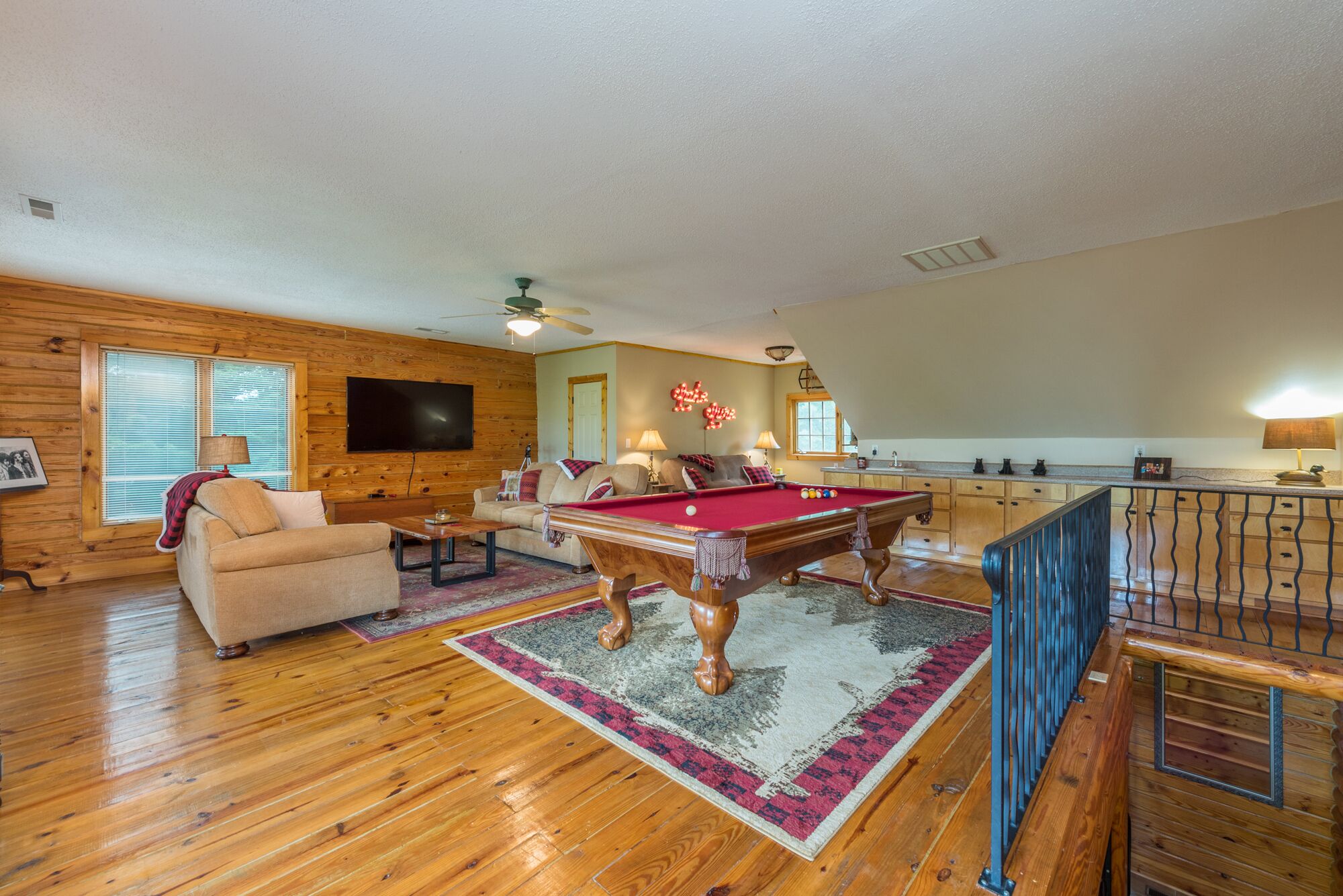 A spacious living room with a pool table, a sofa, and a television.