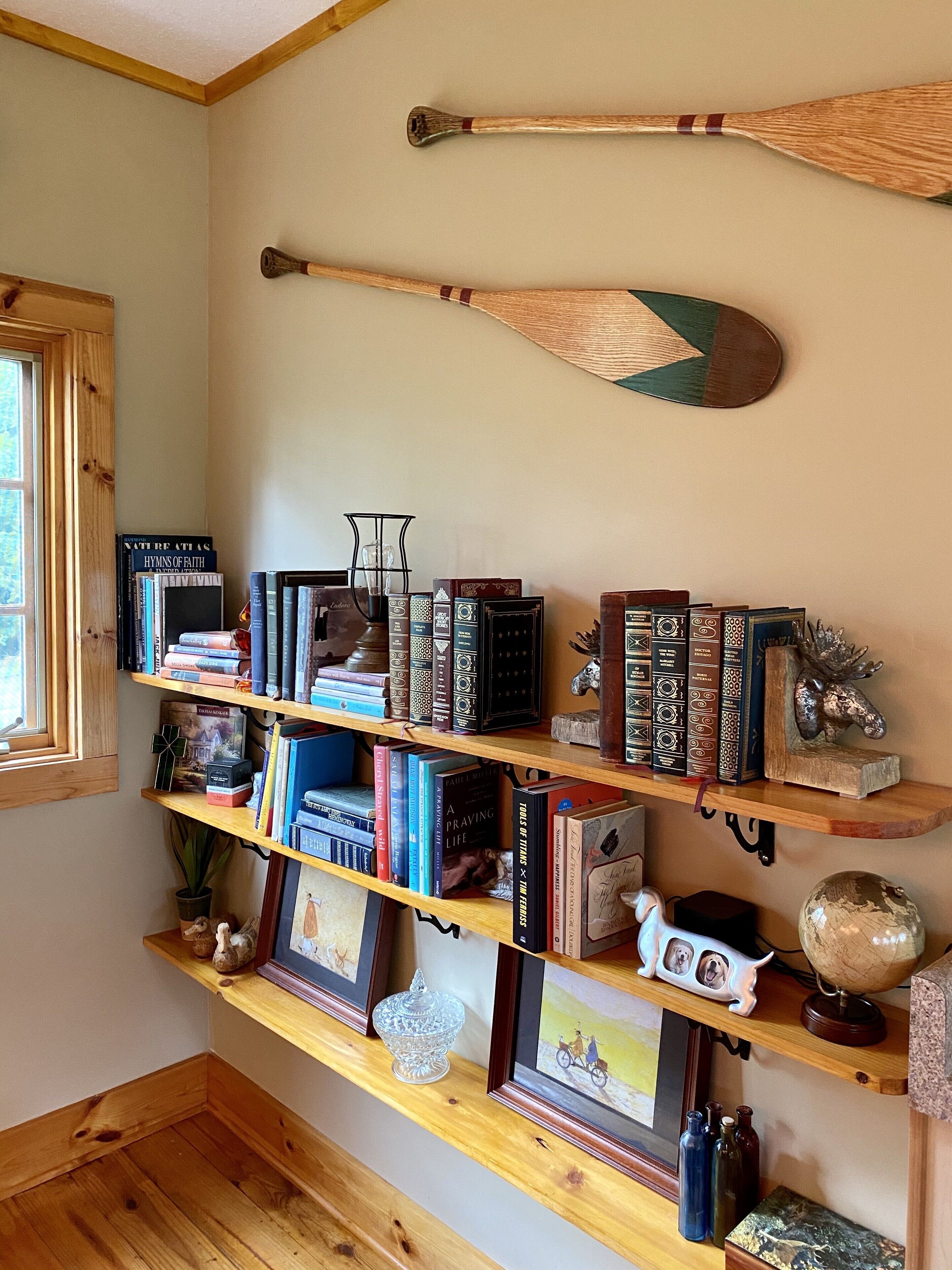 Een boekenplank met verschillende boeken en decoratieve items, waaronder een wereldbol en een beeldhouwwerk van een eland.