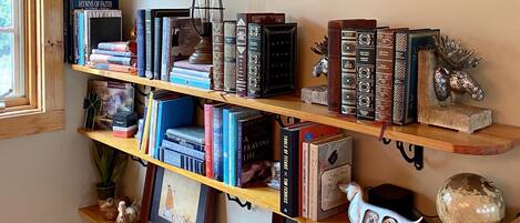 Een boekenplank met verschillende boeken en decoratieve items, waaronder een wereldbol en een beeldhouwwerk van een eland.