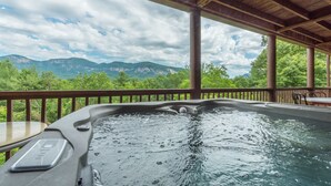 Un bain à remous avec une terrasse en bois et une vue sur les montagnes.