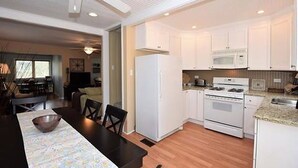 Eine moderne Küche mit weißen Schränken, einer Mikrowelle, einem Backofen und einem Essbereich mit Tisch und Stühlen.