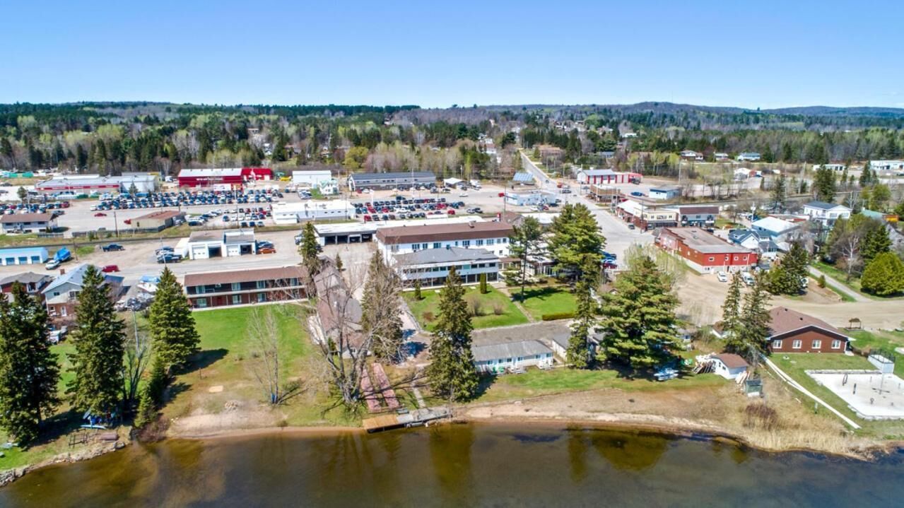 An aerial view of a town with a large parking lot, several buildings, and a body of water.