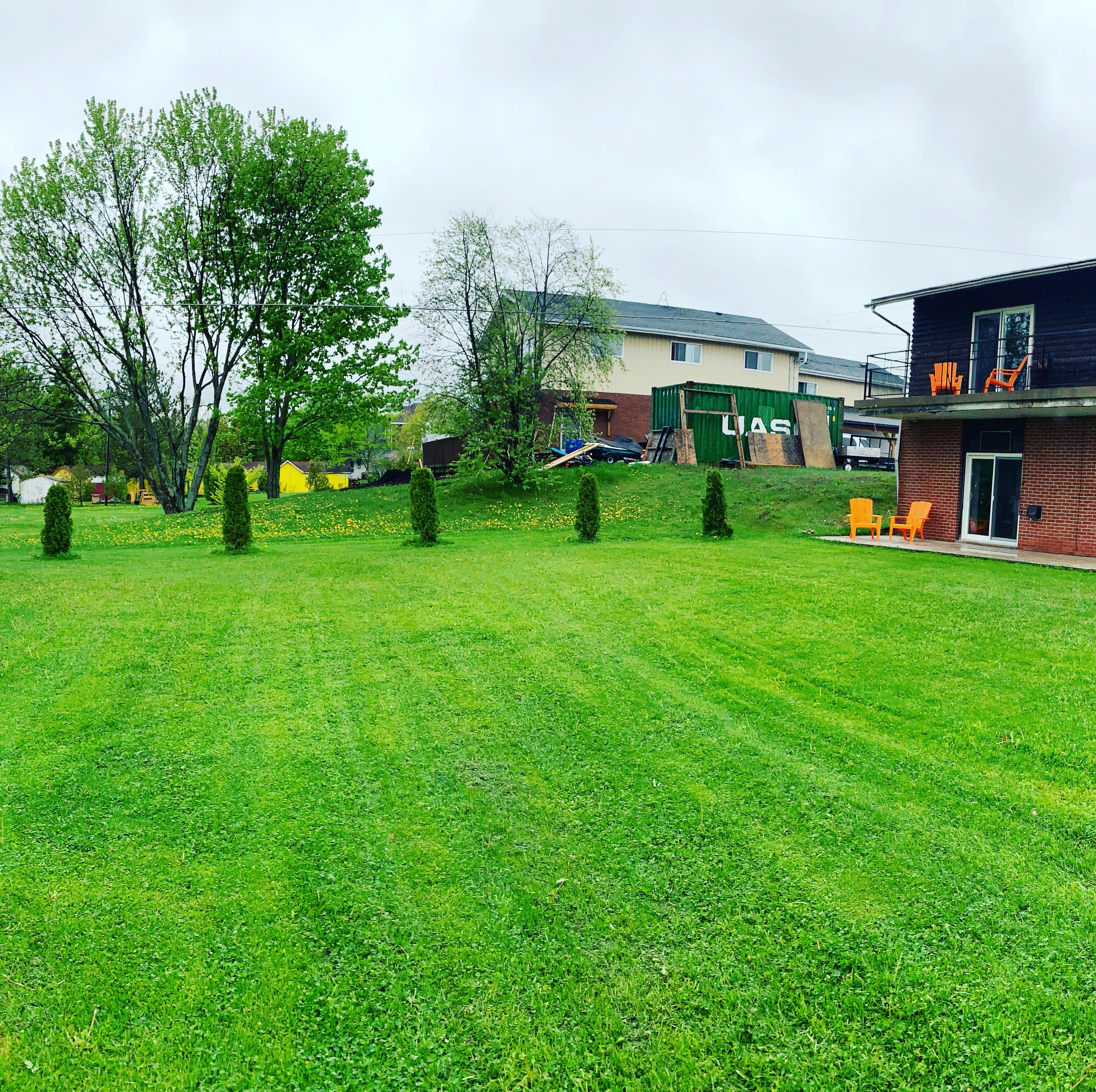 Zona verde con árboles, un edificio con el letrero 'LUGAS' y mesas al aire libre.