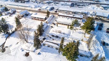An aerial view of a snow-covered parking lot with several buildings, including a large commercial building and smaller residential structures.