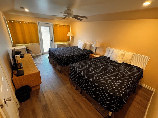 A hotel room with two beds, a desk, a ceiling fan, and a bathroom with a shower curtain. - Caswell Resort Hotel (Sundridge)