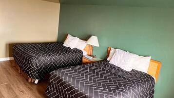 Una habitación con dos camas, un ventilador de techo y una pared verde.