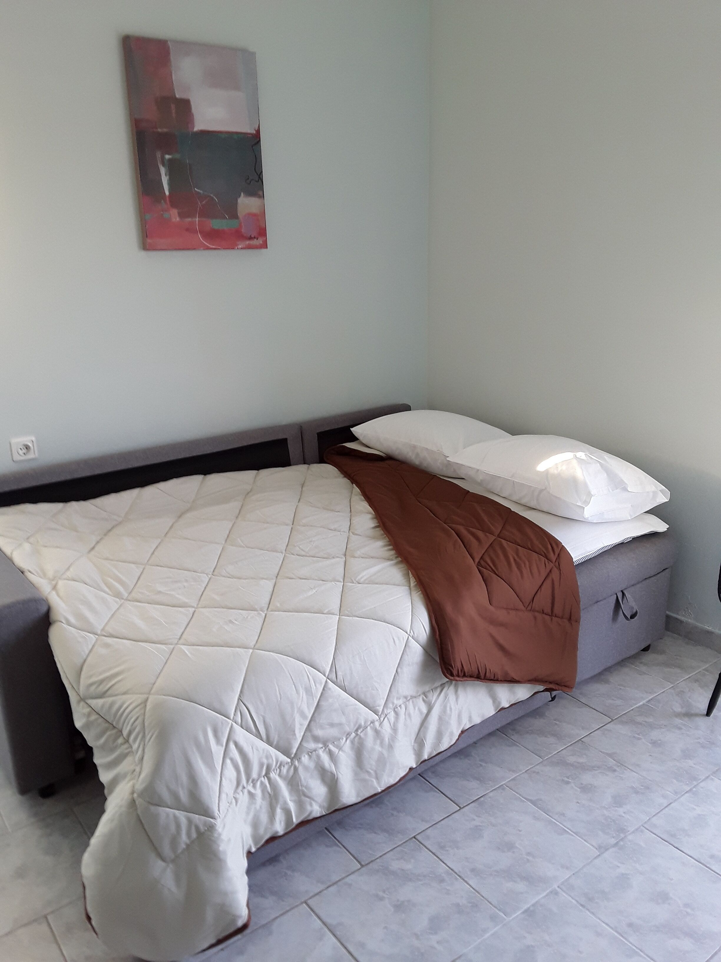 Ein Schlafzimmer mit einem Bett, einem Nachttisch, einem Wandbild und einem Beistelltisch.