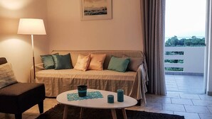 A living room with a sofa, a chair, a lamp, and a table with candles. - Marianos Apartments (Kissamos)