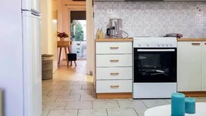 A modern kitchen with white cabinets, a built-in oven, and a coffee maker. - Marianos Apartments (Kissamos)