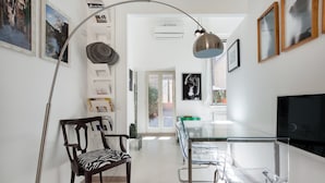 Un espace repas moderne avec une table en verre, des chaises transparentes, une chaise en bois à motifs zébrés et un luminaire suspendu.