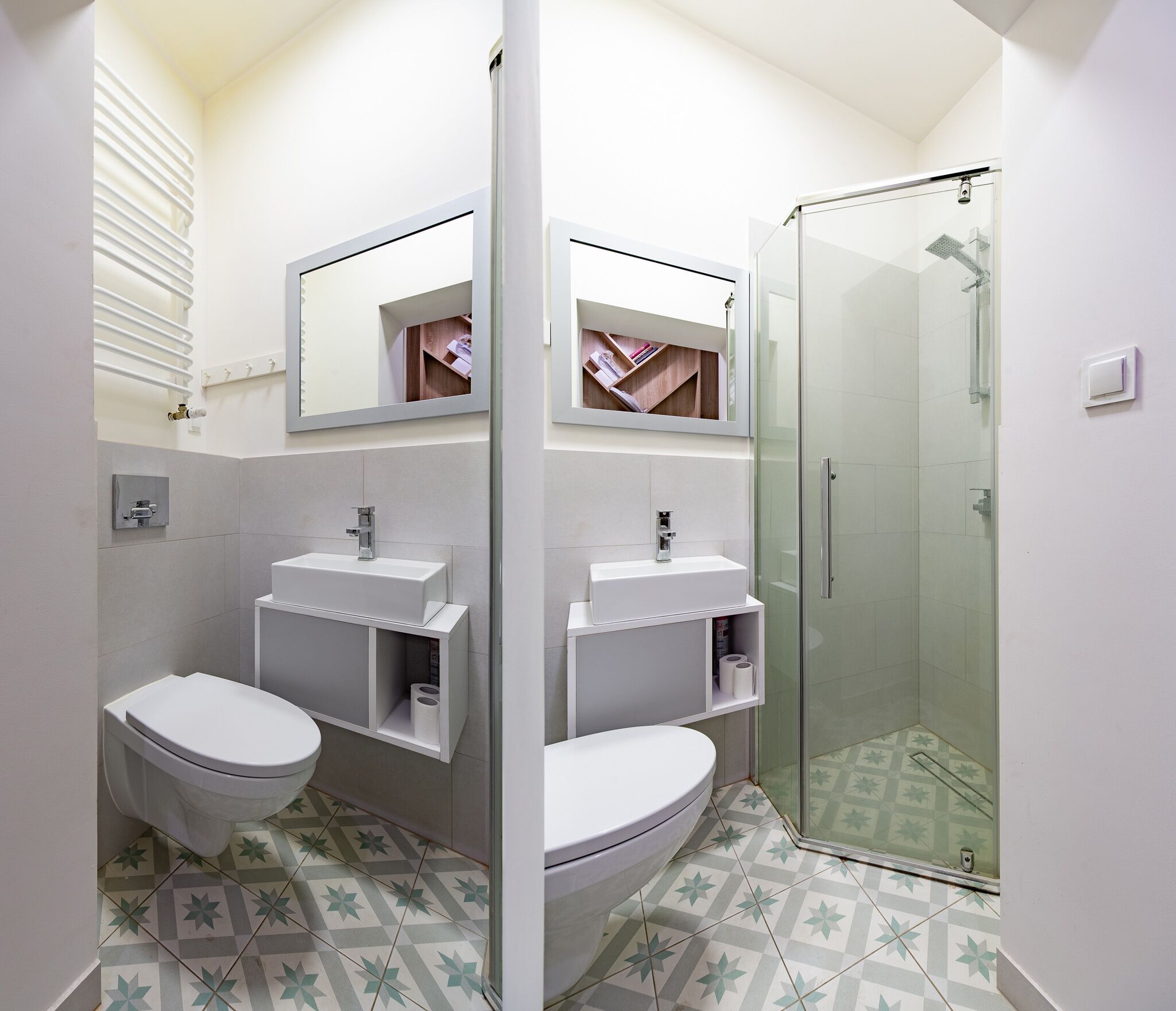 A modern bathroom with two toilets, a shower, and a vanity with a mirror.
