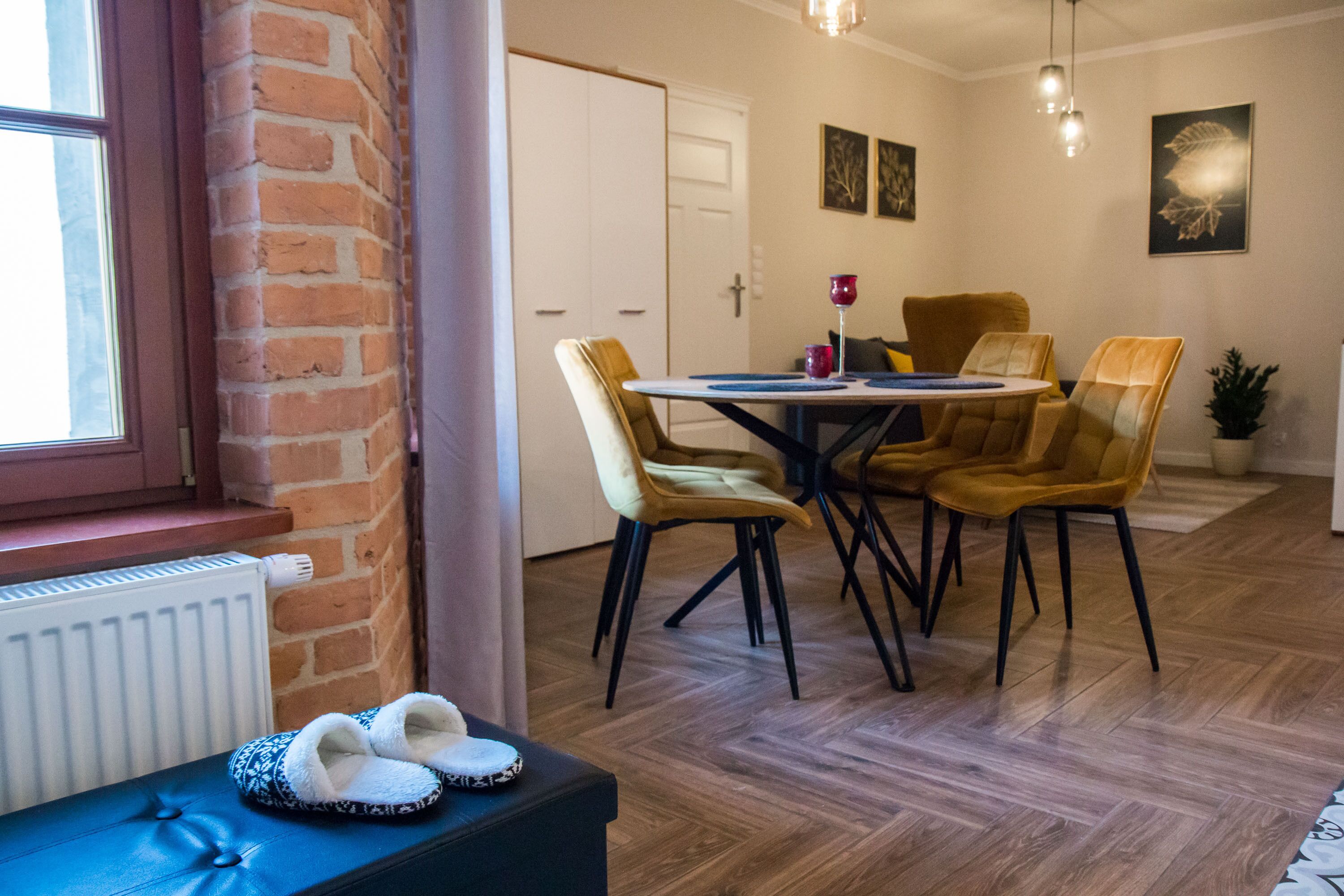 A dining area with a brick wall, a white door, and a table with four chairs.