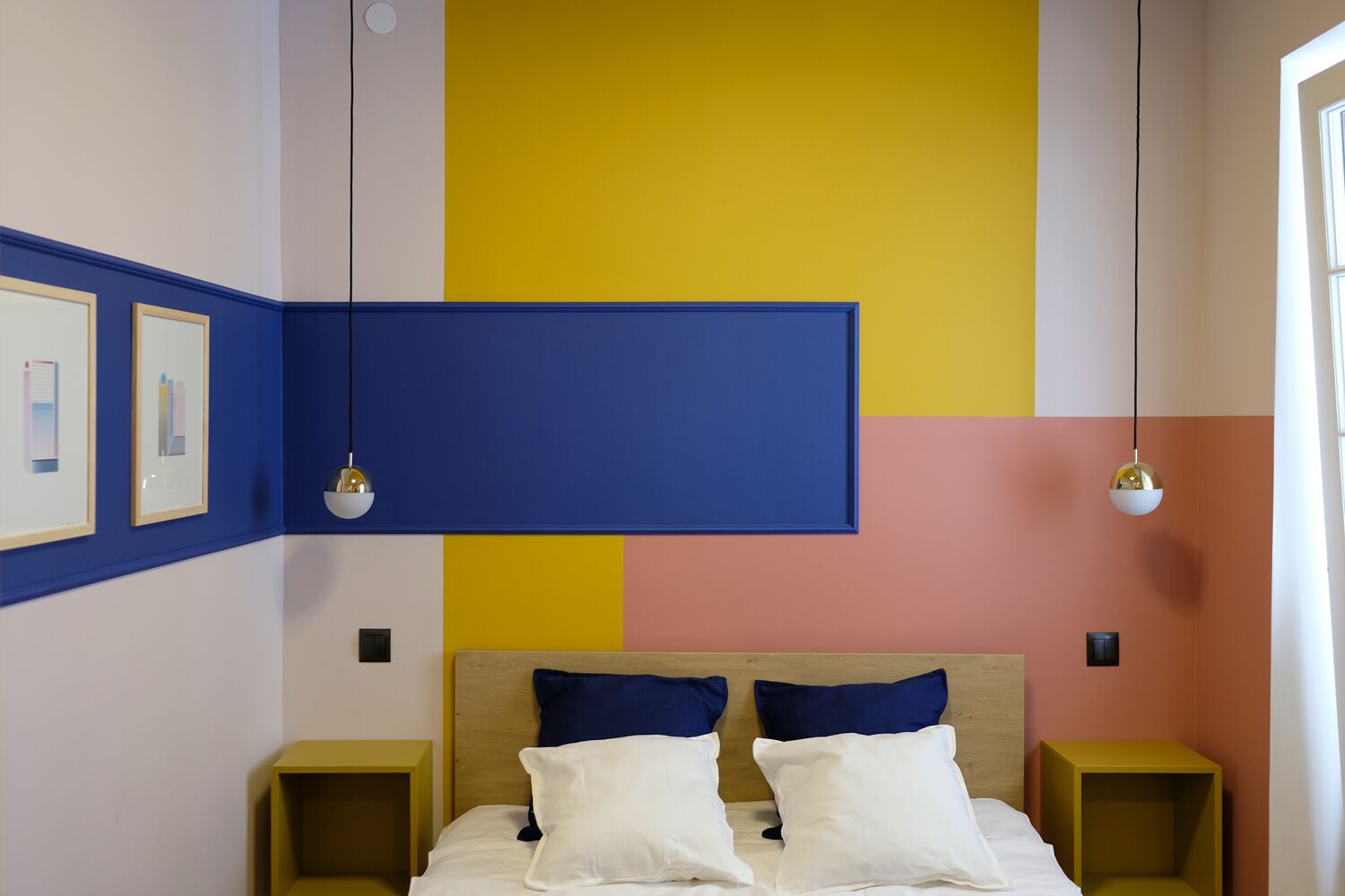 A bedroom with a bed, two bedside tables, and a wall with a large blue panel.
