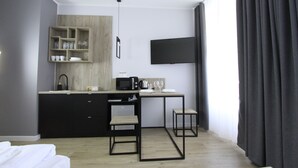 Habitación de hotel moderna con kitchenette, televisión de pantalla plana, cama y vistas al exterior.