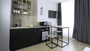 Una cocina moderna con gabinetes negros, encimera de madera, microondas y una pequeña mesa.