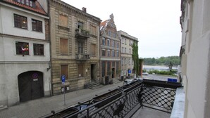 Vista desde un balcón con vistas a una calle con edificios históricos, un río y un estacionamiento.