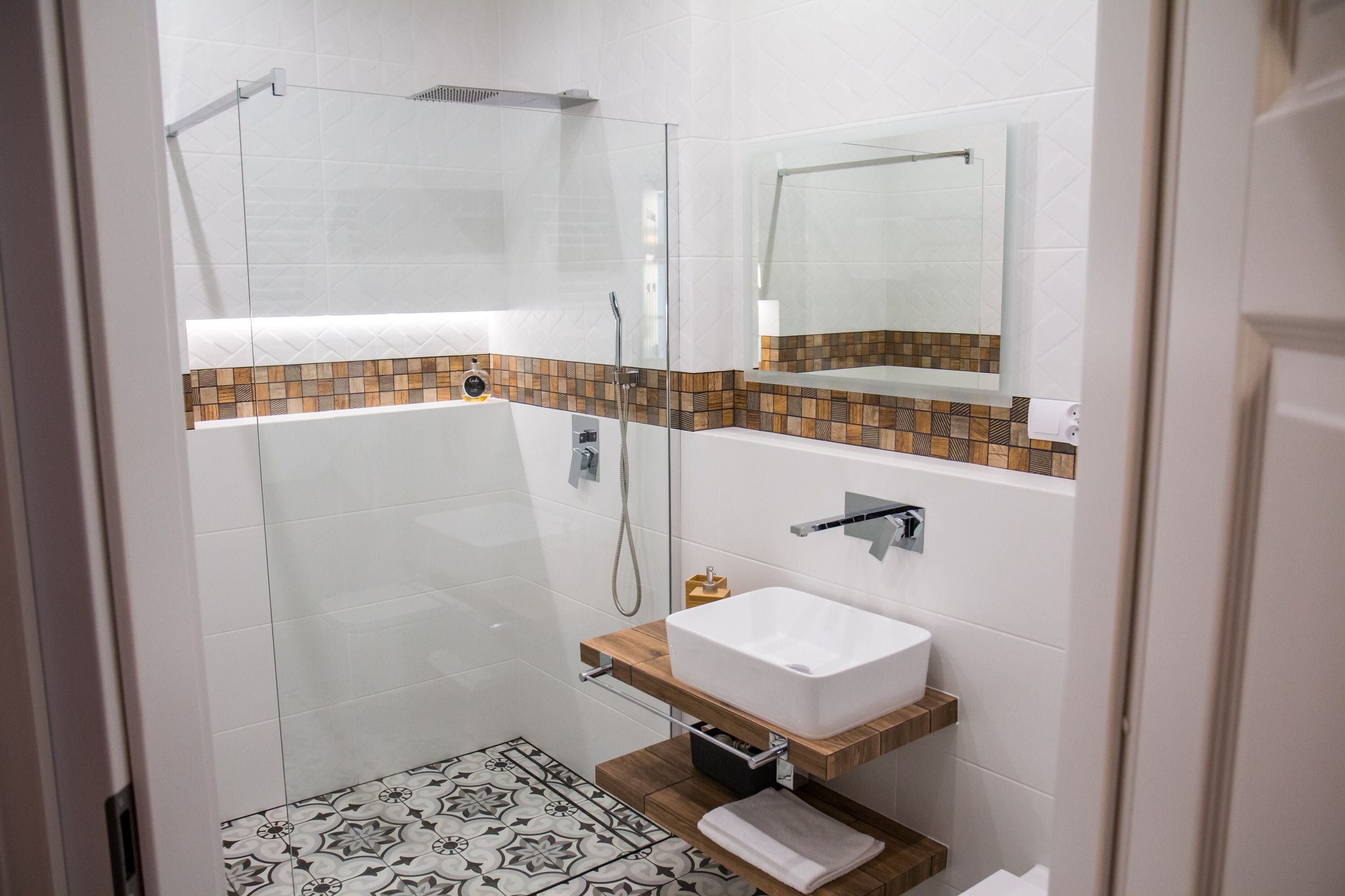 A modern bathroom with a glass-enclosed shower, a white sink, and a tiled floor.