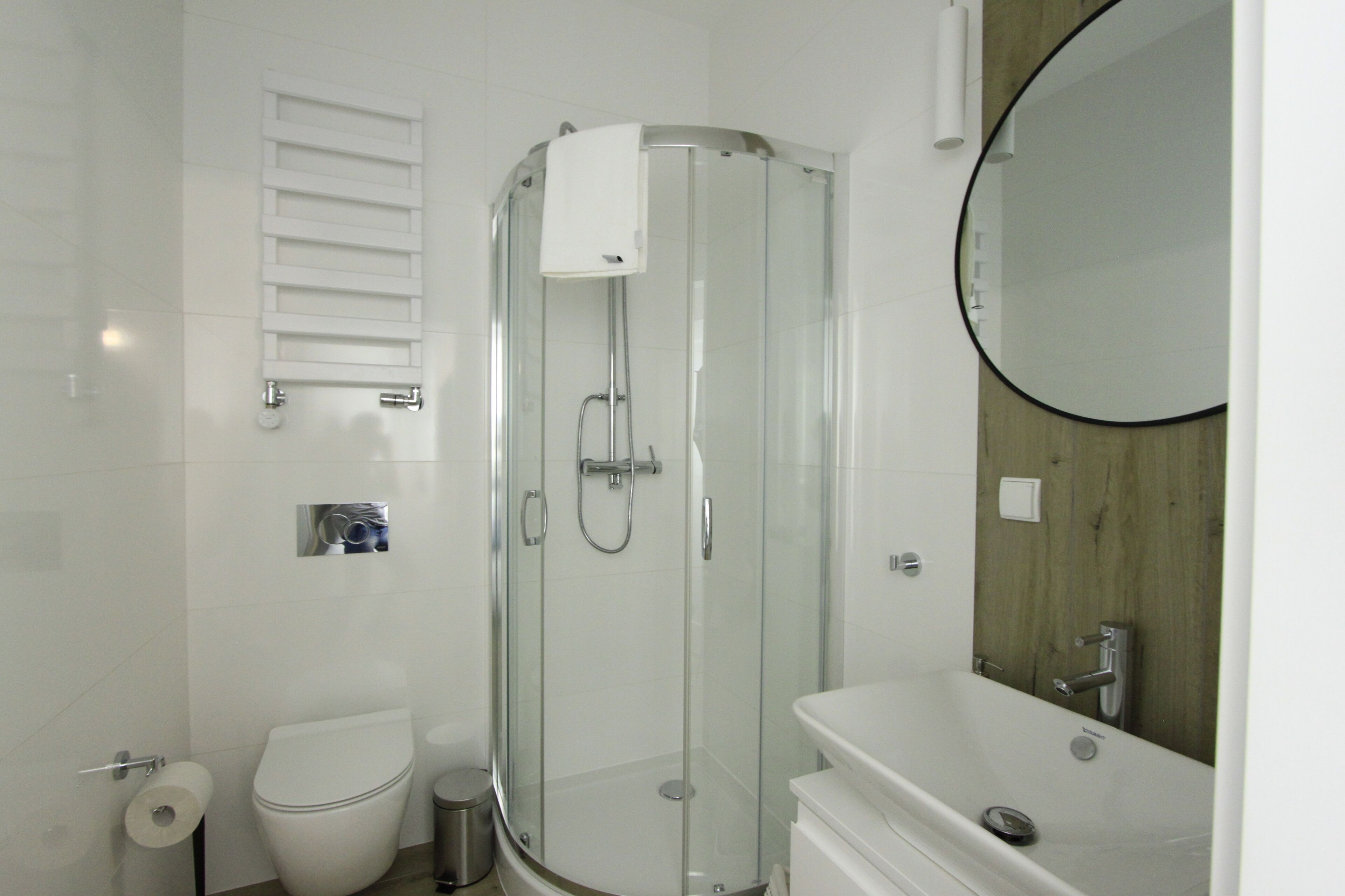 Un baño moderno con ducha de vidrio, inodoro y lavabo con espejo.