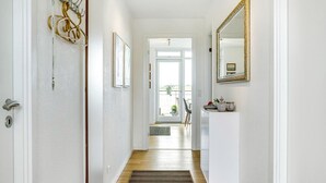 A hallway with a wooden floor, a white door, a wall-mounted mirror, and a door with a keyhole. - 2 bedroom nice apartment in Hejls (Hejls)