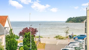A coastal residential area with a view of the sea, parked cars, and a pedestrian pathway. - 2 bedroom nice apartment in Hejls (Hejls)