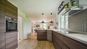 Une cuisine moderne dotée d’un grand îlot central, de meubles de couleur sombre en bois et d’une hotte en acier inoxydable.