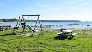 Une zone herbeuse avec des tables de pique-nique et une balançoire, située au bord d’un lac.