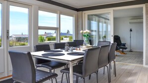 Un espace repas comprenant une table et des chaises, de grandes fenêtres et une vue sur l’extérieur.