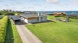 Une maison moderne avec une allée pavée, un petit jardin et une vue sur la mer.