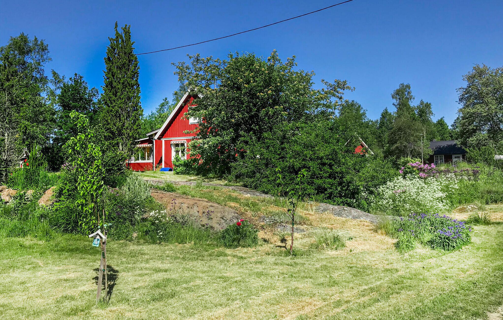 Ein rotes Haus, umgeben von üppigem Grün und Bäumen.