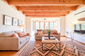 A cozy living room with a wooden ceiling, two sofas, a coffee table, and a TV. - Meadow Cabin on Sylamore Creek (Mountain View)